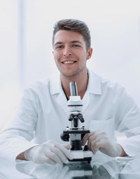 young scientist with a microscope sitting at a laboratory table