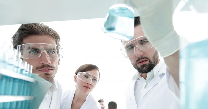 closeup. scientist and assistant studying the solution in the glass tube