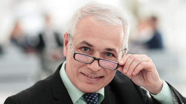 closeup of a senior businessman adjusting his glasses