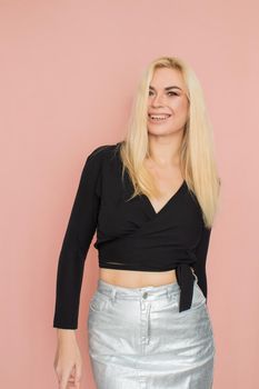 Fashion model woman in fashionable clothes on pink background. Wearing stylish clothing, black blouse, silver skirt. Posing in studio