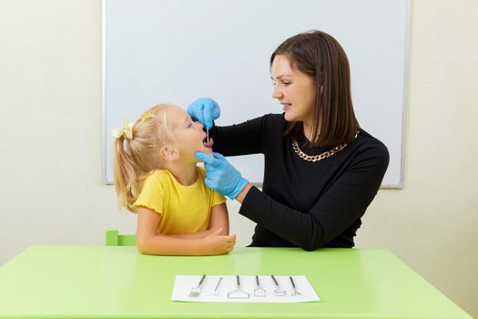 Speech therapist working with little girl in office training pronunciation