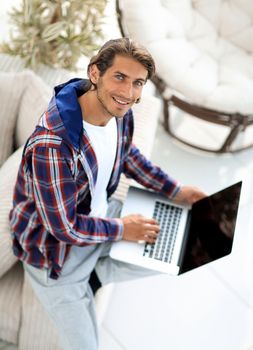 young man working on laptop and looking at camera. view from above