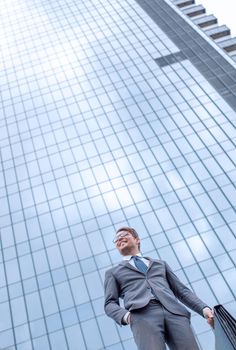 business man with briefcase standing on grass near tall office building