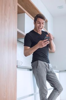 smiling casual man looking at the screen of his smartphone