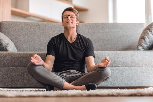 casual guy sitting in Lotus position on carpet in his living room