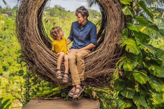 Bali trend, straw nests everywhere. Child friendly place. Happy family enjoying their travel around Bali island, Indonesia. Making a stop on a beautiful hill. Photo in a straw nest, natural environment. Lifestyle. Traveling with kids concept. What to do with children