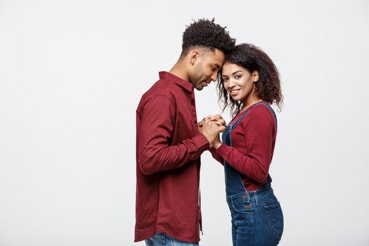 Side view of beautiful African American young couple in classic shirts holding hands, looking at each other and smiling.
