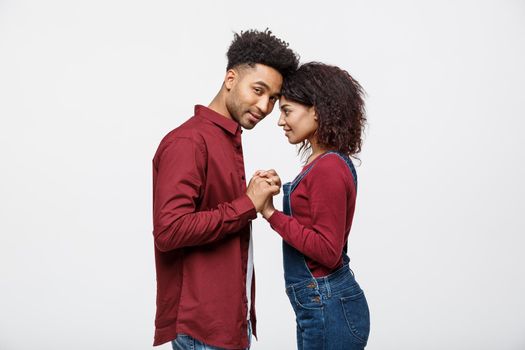Side view of beautiful African American young couple in classic shirts holding hands, looking at each other and smiling.