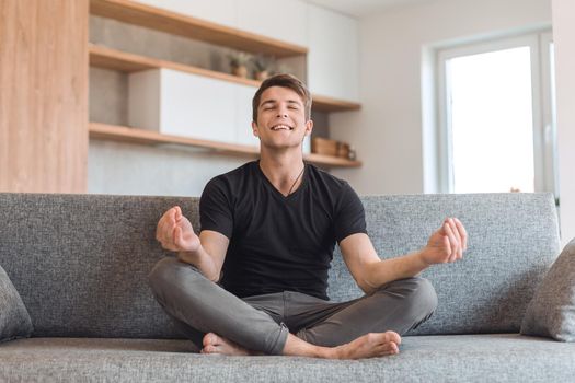 young man sitting in Lotus position on his new sofa