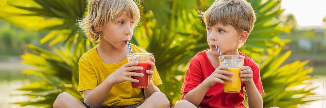 BANNER, LONG FORMAT Two boys drink healthy smoothies against the backdrop of palm trees. Mango and watermelon smoothies. Healthy nutrition and vitamins for children