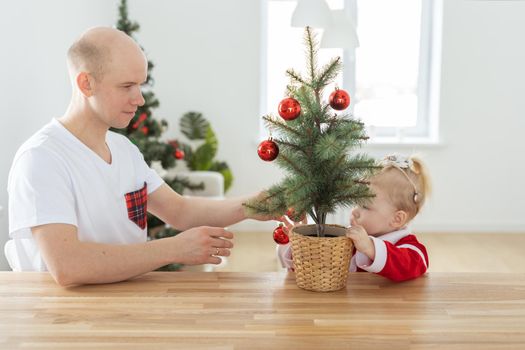 Child with cochlear implant hearing aid having fun with father and small christmas tree - diversity and deafness treatment and medical innovative technologies