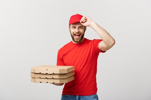 Delivery Concept: Handsome pizza delivery man courier in red uniform with cap holding pizza boxes. Isolated on white.