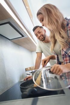 young husband and wife cook dinner together