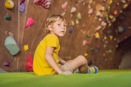 Boy resting after climbing a rock wall indoor