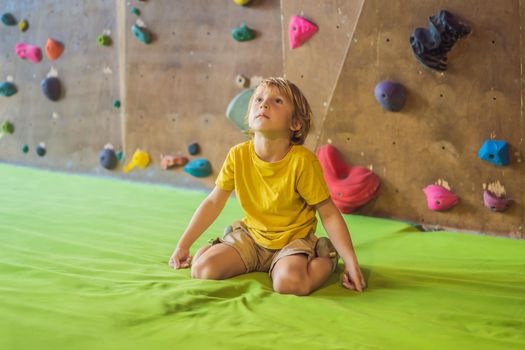 Boy resting after climbing a rock wall indoor