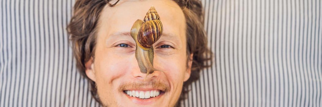 Young man makes a face mask with snail mucus. Snail crawling on a face mask. SPA for man, SPA for all BANNER, LONG FORMAT
