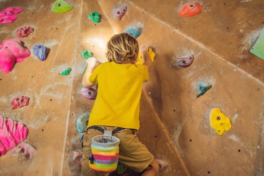 little boy climbing a rock wall in special boots. indoor