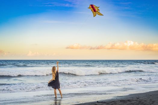 A young woman launches a kite on the beach. Dream, aspirations, future plans