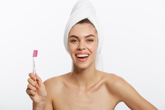 Smiling woman brushing her teeth with towel on her head. A great smile