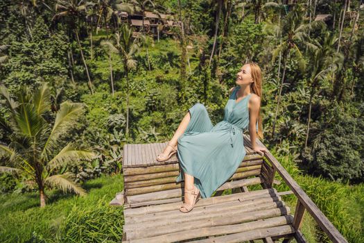Beautiful young woman walk at typical Asian hillside with rice farming, mountain shape green cascade rice field terraces paddies. Ubud, Bali, Indonesia. Bali travel concept