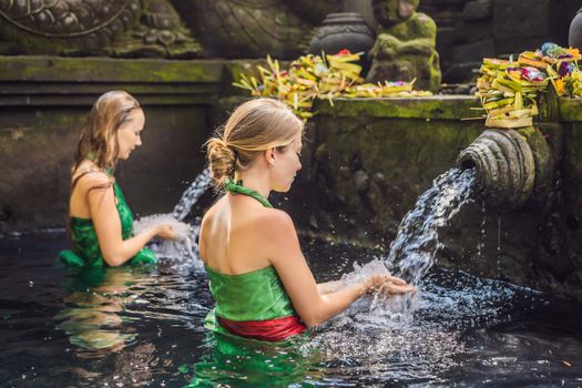 Two women in holy spring water temple in bali. The temple compound consists of a petirtaan or bathing structure, famous for its holy spring water