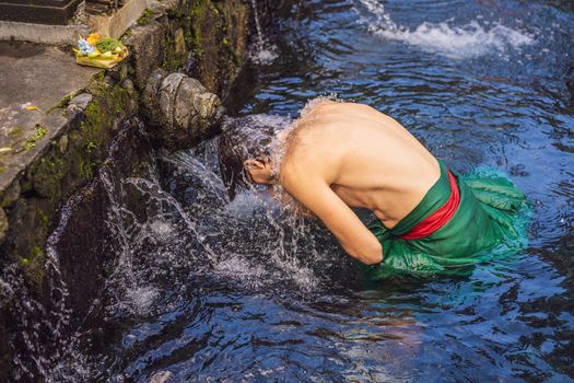 Man in holy spring water temple in bali. The temple compound consists of a petirtaan or bathing structure, famous for its holy spring water
