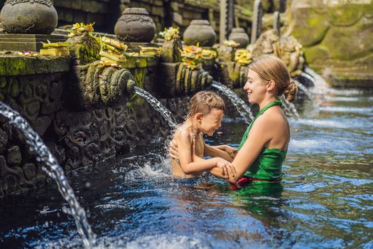 Mother and son in holy spring water temple in bali. The temple compound consists of a petirtaan or bathing structure, famous for its holy spring water