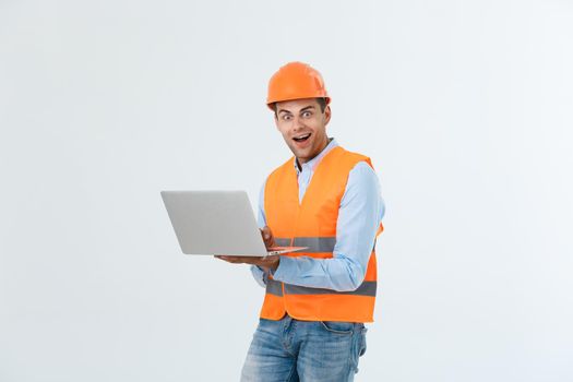Adult man constructor surprised and working with laptop in helmet indoors.