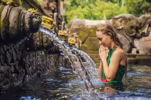 Woman in holy spring water temple in bali. The temple compound consists of a petirtaan or bathing structure, famous for its holy spring water