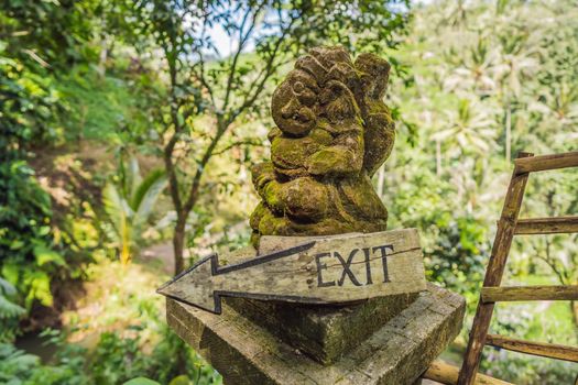 Balinese statue and exit sign against the backdrop of nature