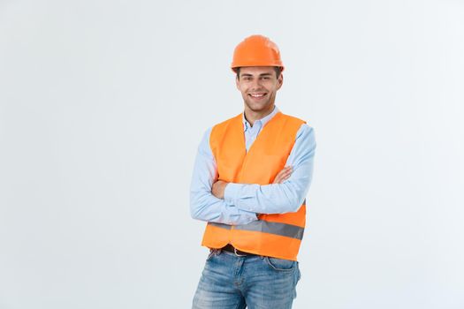 Smiling construction engineer posing with arms crossed. Isolated over grey background