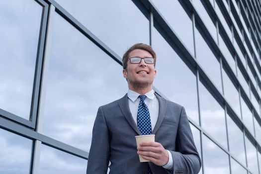 happy young businessman standing near tall office building
