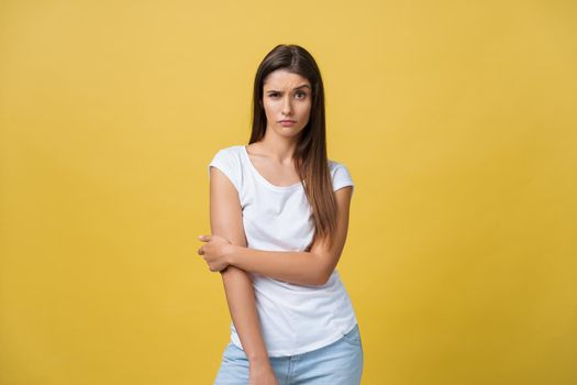 Smiling beautiful young woman in white shirt looking to camera. Three quarter length studio shot on yellow background.