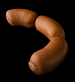 Three boiled sirloin sausages on a black background isolated