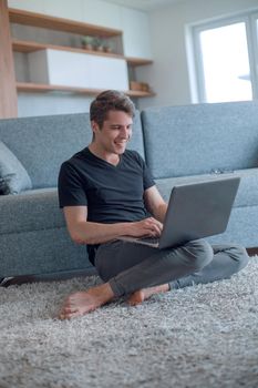 young man typing on his laptop in cozy living room