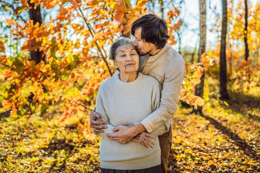 Grandmother and adult grandson hugging in autumn park