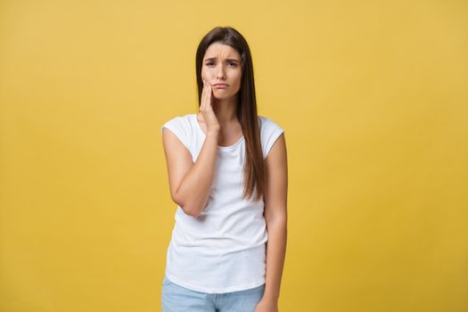 young woman has a toothache, studio photo isolated on a yellow background