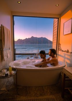 man and woman in bath tub jaccuzi on vacation, couple man and woman in bath tub looking out over the ocean of Cape Town South Africa during vacation