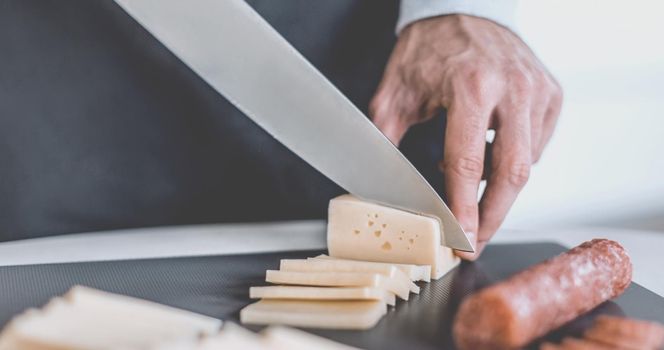 close up. man slicing cheese for sandwiches