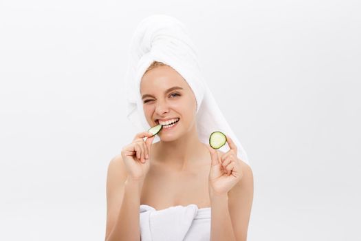 Young beautiful nude girl smiling hiding eyes behind cucumber slices over white background. Beauty skincare and cosmetology