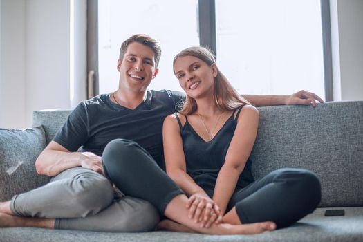 happy young couple sitting on the couch in their new apartment .