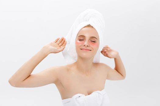 Young beautiful yawning woman with collagen pads under her eyes on a light background. Spa, eye skin care.