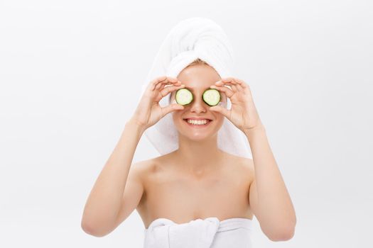Beautiful woman holding slices of cucumber in front of her eyes