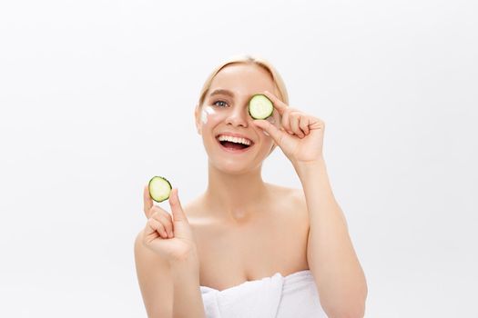 Beautiful woman holding slices of cucumber in front of her eyes