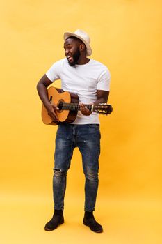 Full-length photo of excited artistic man playing his guitar. Isolated on yellow background.