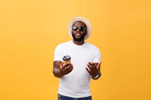 Stylish young african american man holding cup of take away coffee isolated over yellow background.