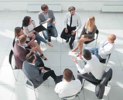 business training participants sitting in a circle and looking at the camera