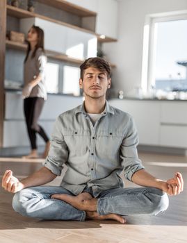 young man sitting in Lotus position on kitchen floor