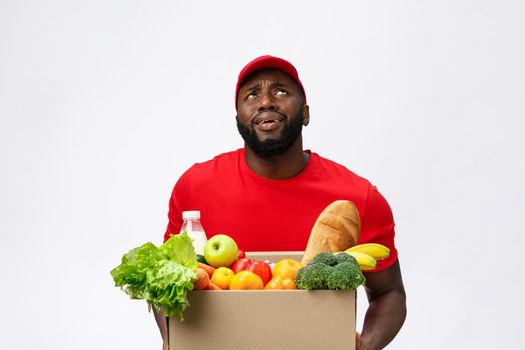 Portrait of delivery african american man in red shirt. he lifting heavy weight grocery boxes against having a isolated on the white background.