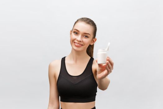 Smiling blonde sport woman holding bottle of medicine on white background